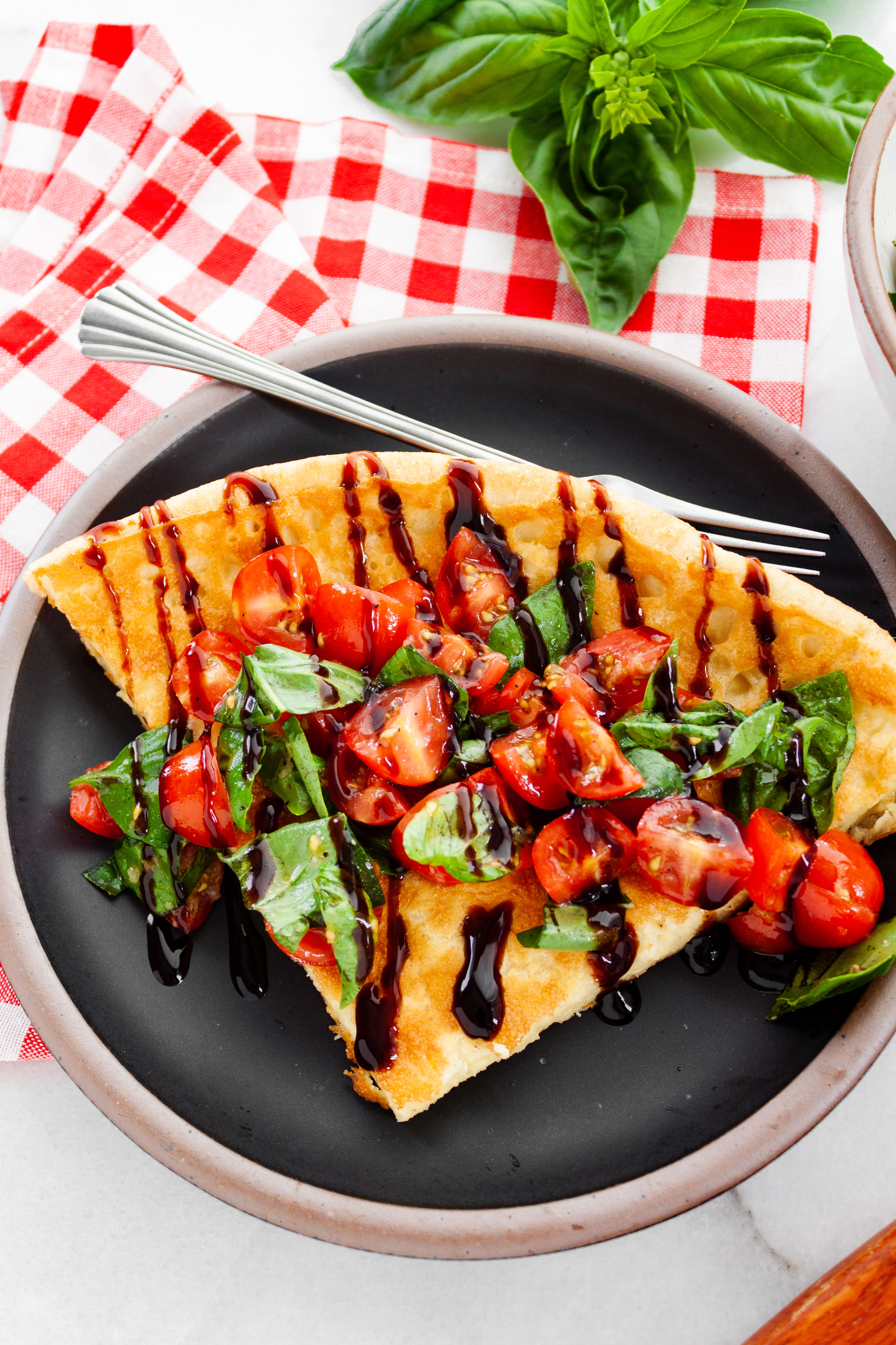 Caprese Dutch Baby served on a black plate with a fork