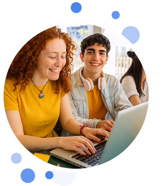 Two young people smiling and working on a laptop together in a bright room.