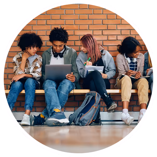 Four students sitting on a bench with a laptop and notebooks.