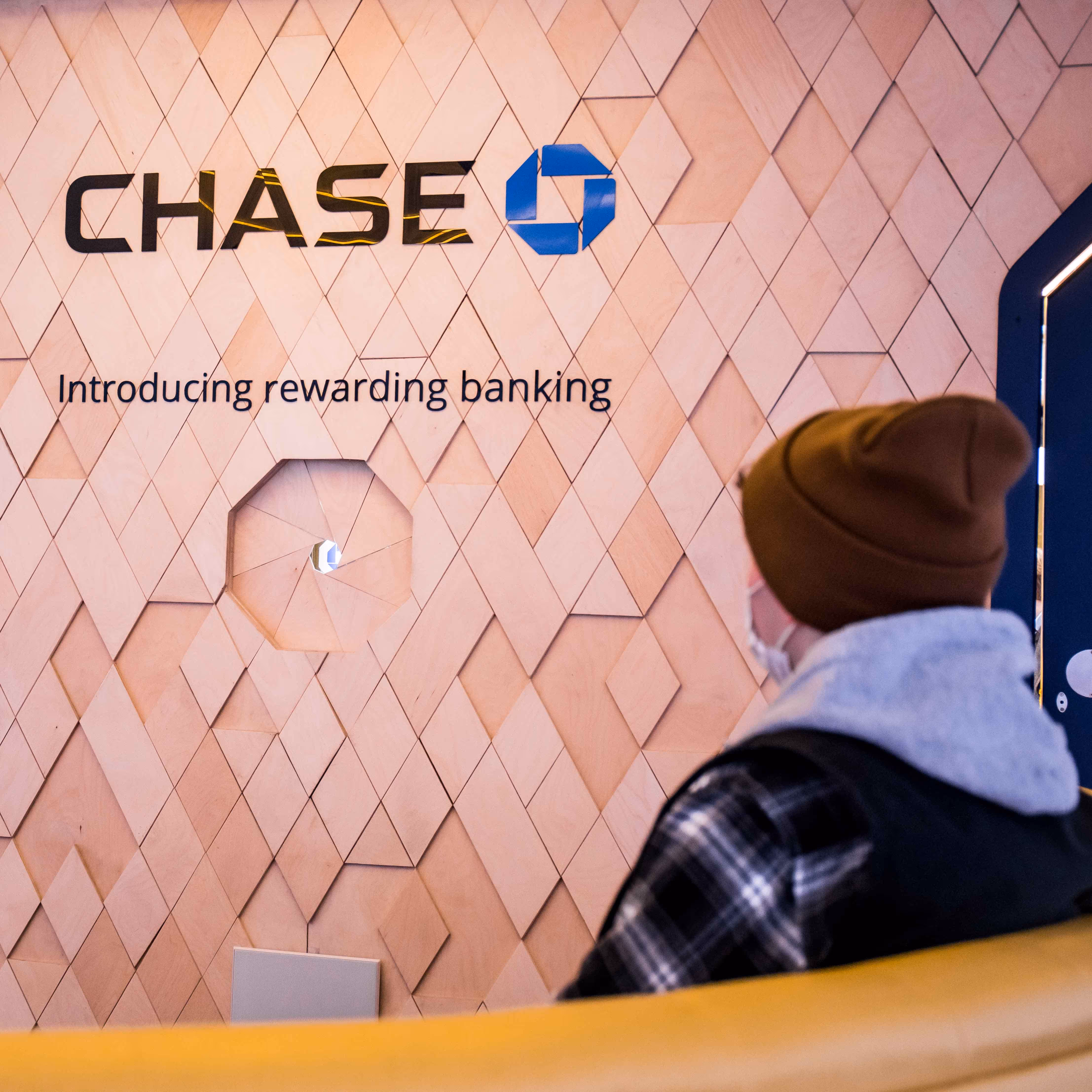 A man sits in front of the Chase bank logo, with the copy line underneath that reads, Introducing Rewarding Banking.
