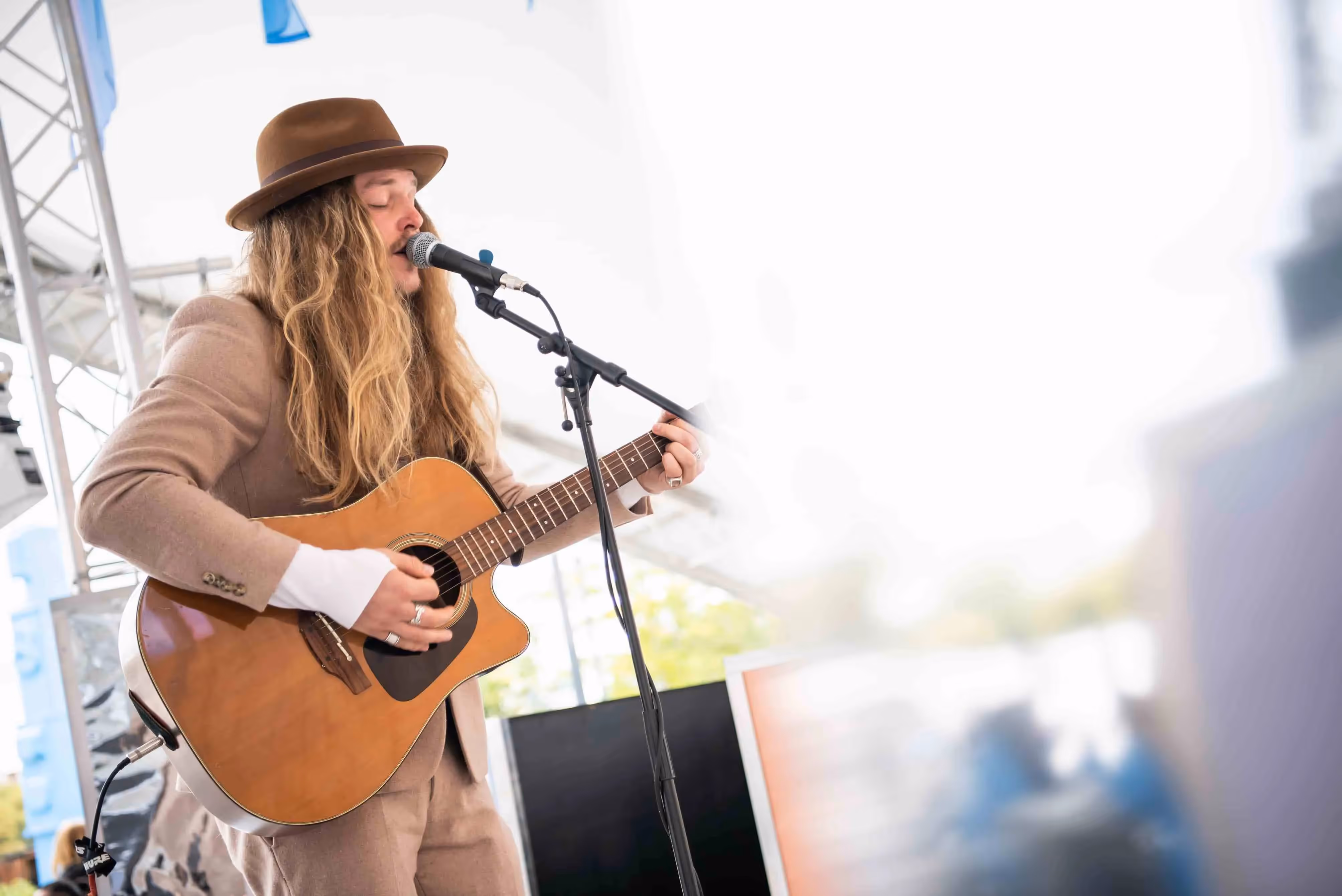 A local performer plays the guitar whilst singing into a microphone at Battersea Power Station launch event.