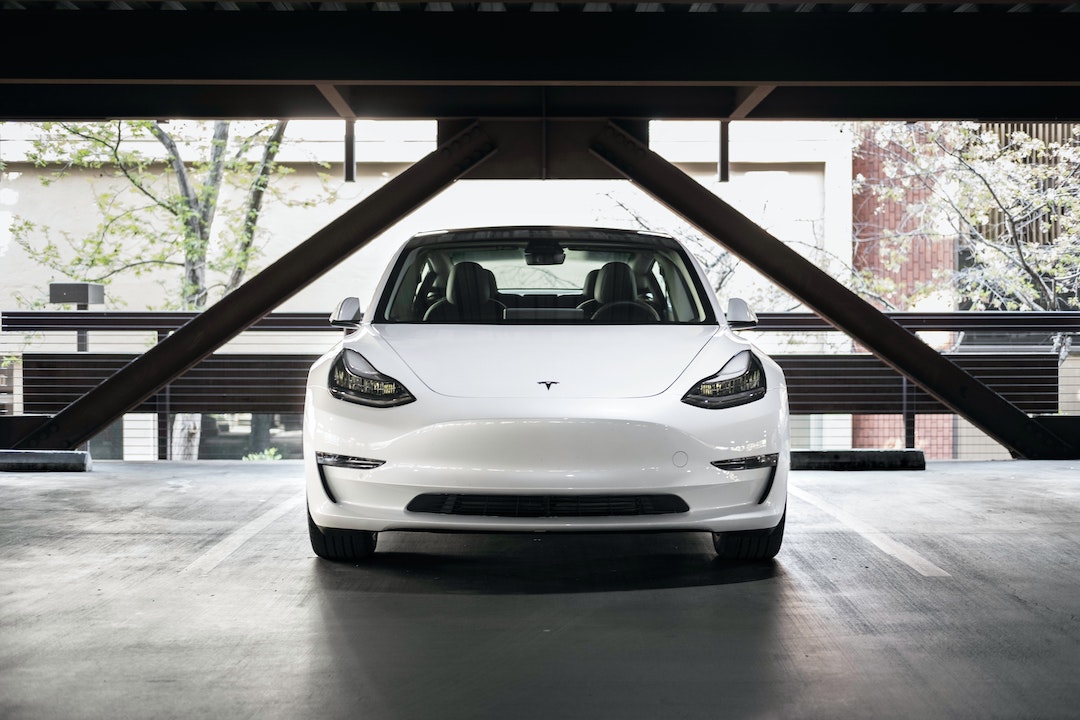 A white Tesla Model 3 parked head-on in a parking space