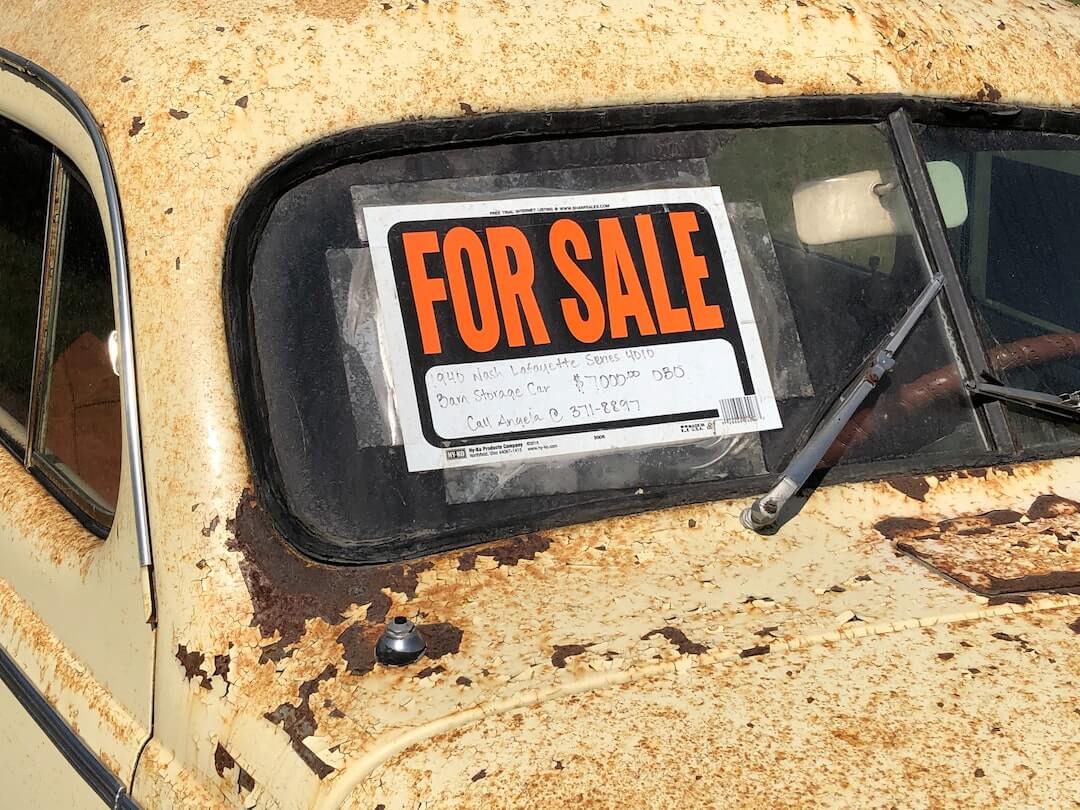 A for sale sign in the windscreen of a rusty car