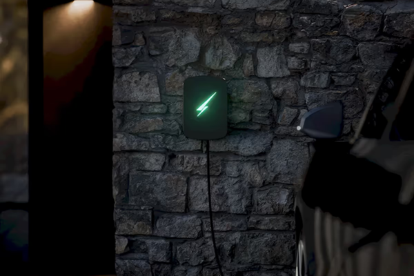 Home EV charger glowing green, showing convenient electric car charging for employees