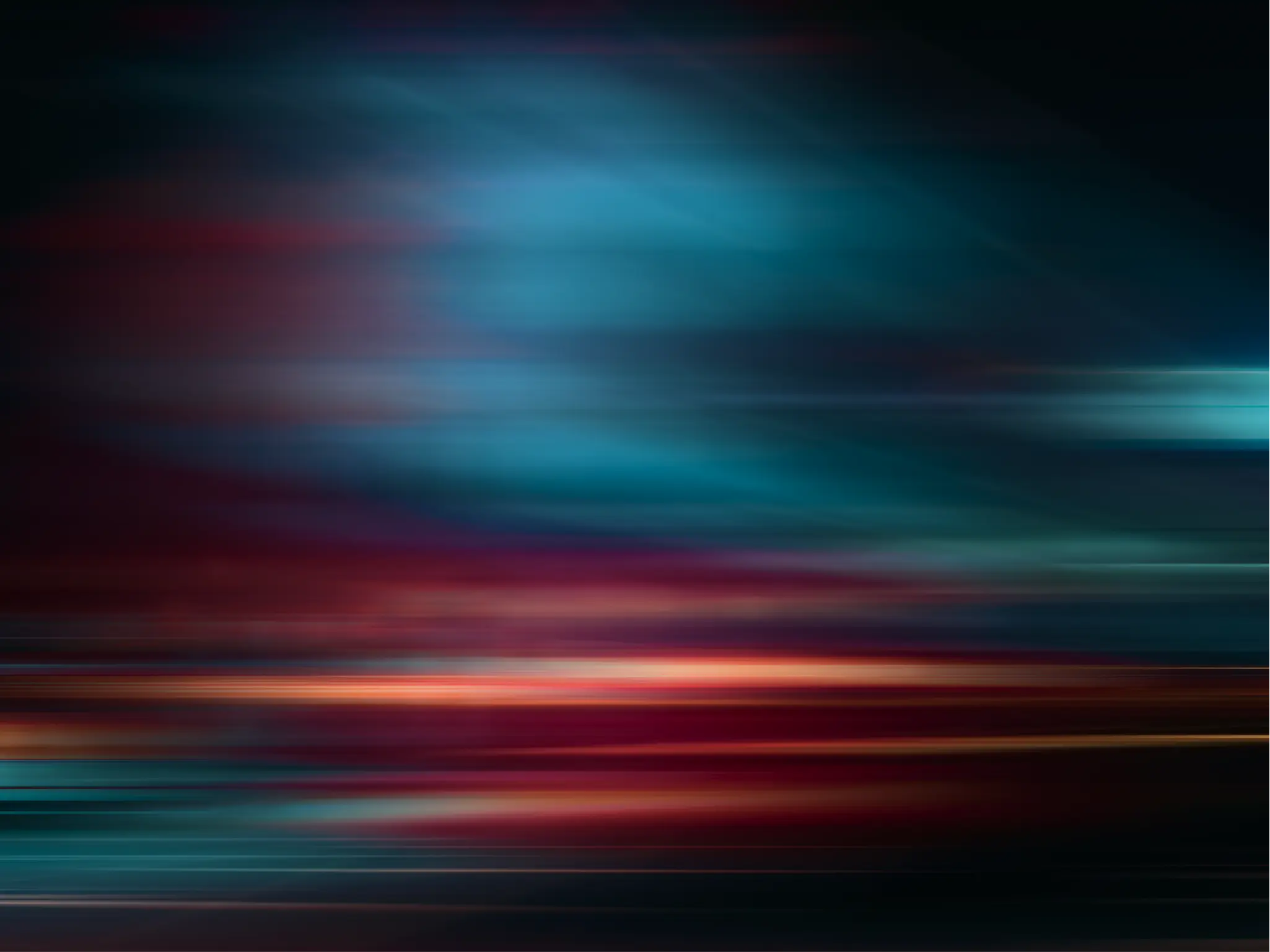 Abstract motion-blur texture with sweeping horizontal streaks of teal, red, and orange light against a dark background, creating a sense of speed and movement.