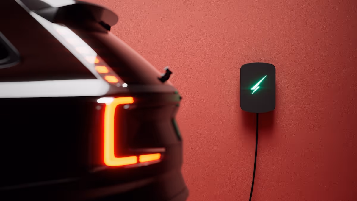  Electric car plugged into a wall-mounted home charging point, with rear lights illuminated.