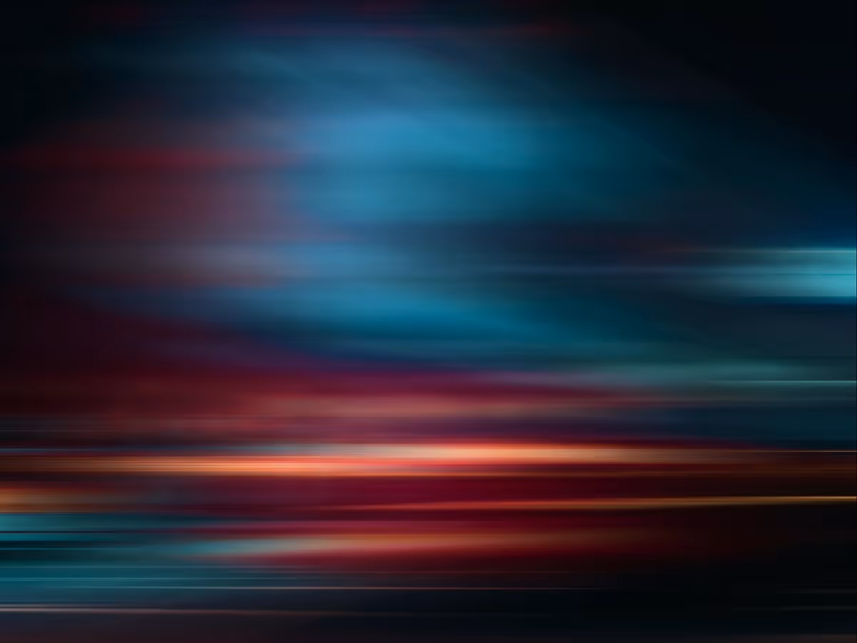Abstract motion-blur texture with sweeping horizontal streaks of teal, red, and orange light against a dark background, creating a sense of speed and movement.