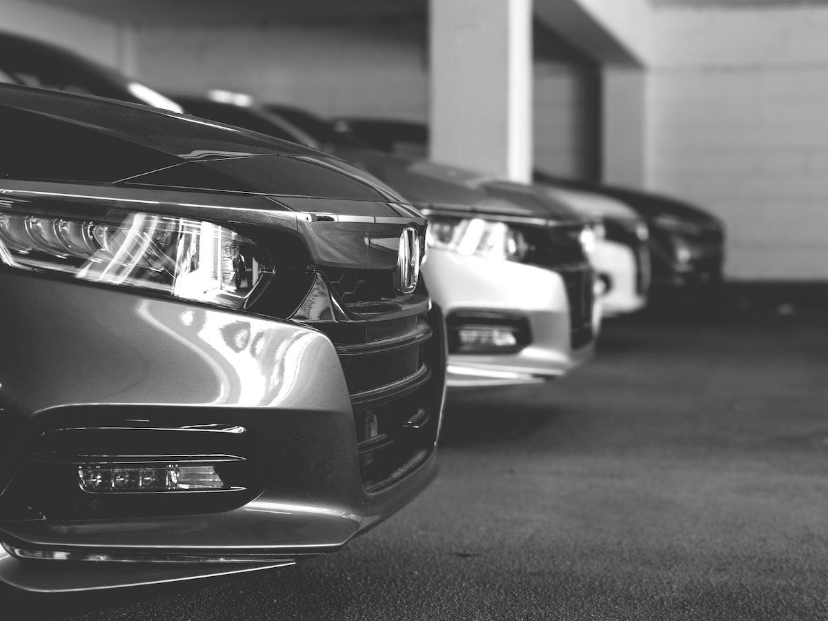 A side view of three cars parked up. It's a corporate setting. The image is in black and white. 
