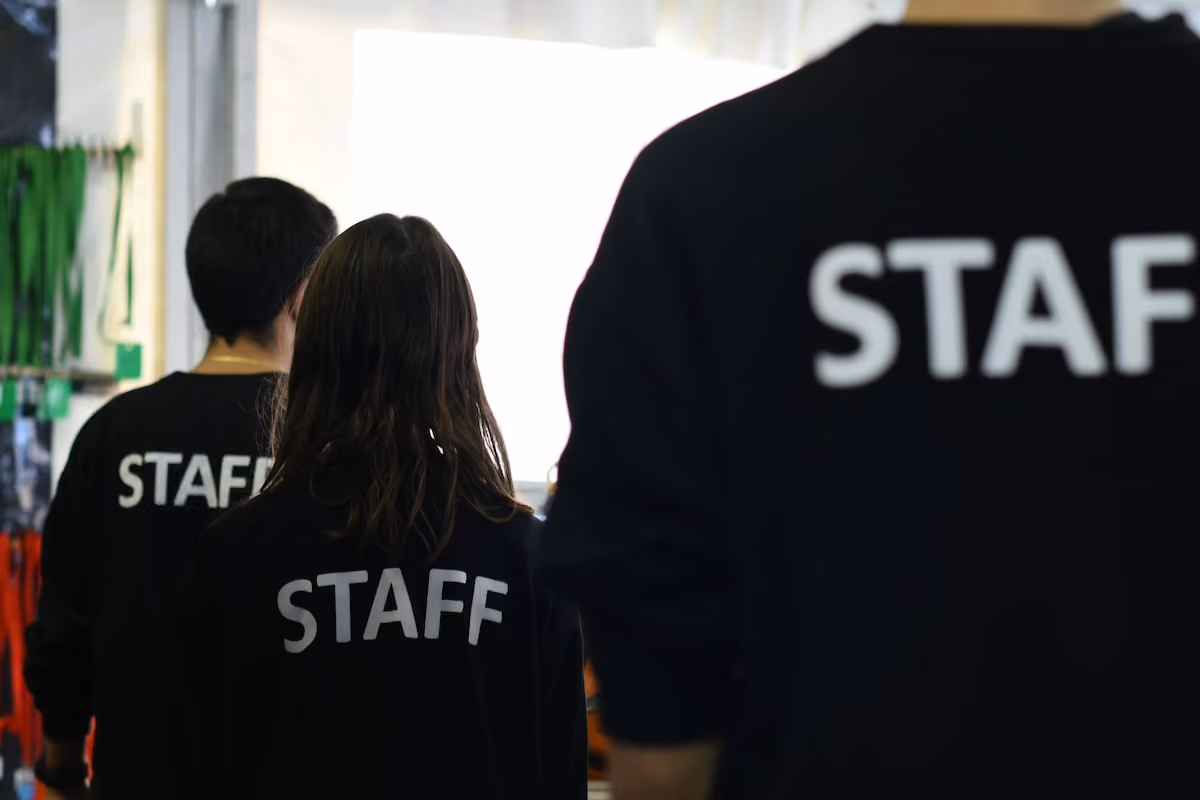 Three employees with 'STAFF' on the back of their black shirts, facing away.