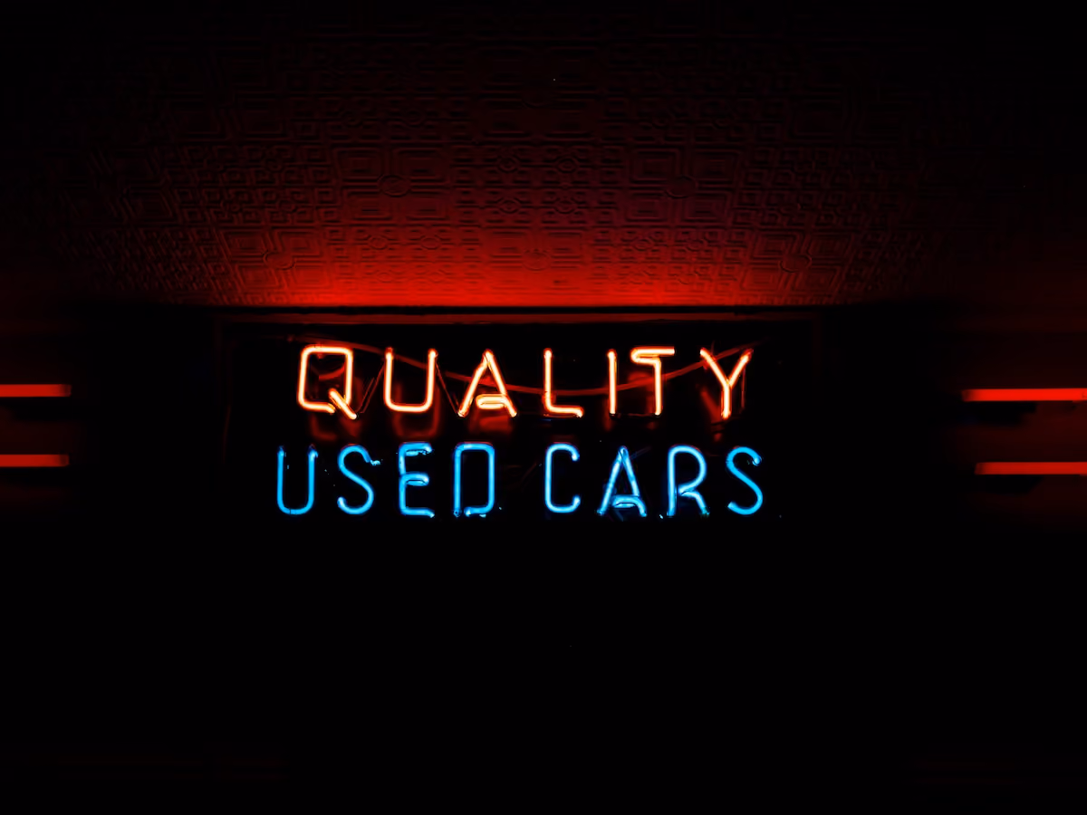 A neon sign displaying the text 'QUALITY USED CARS'
