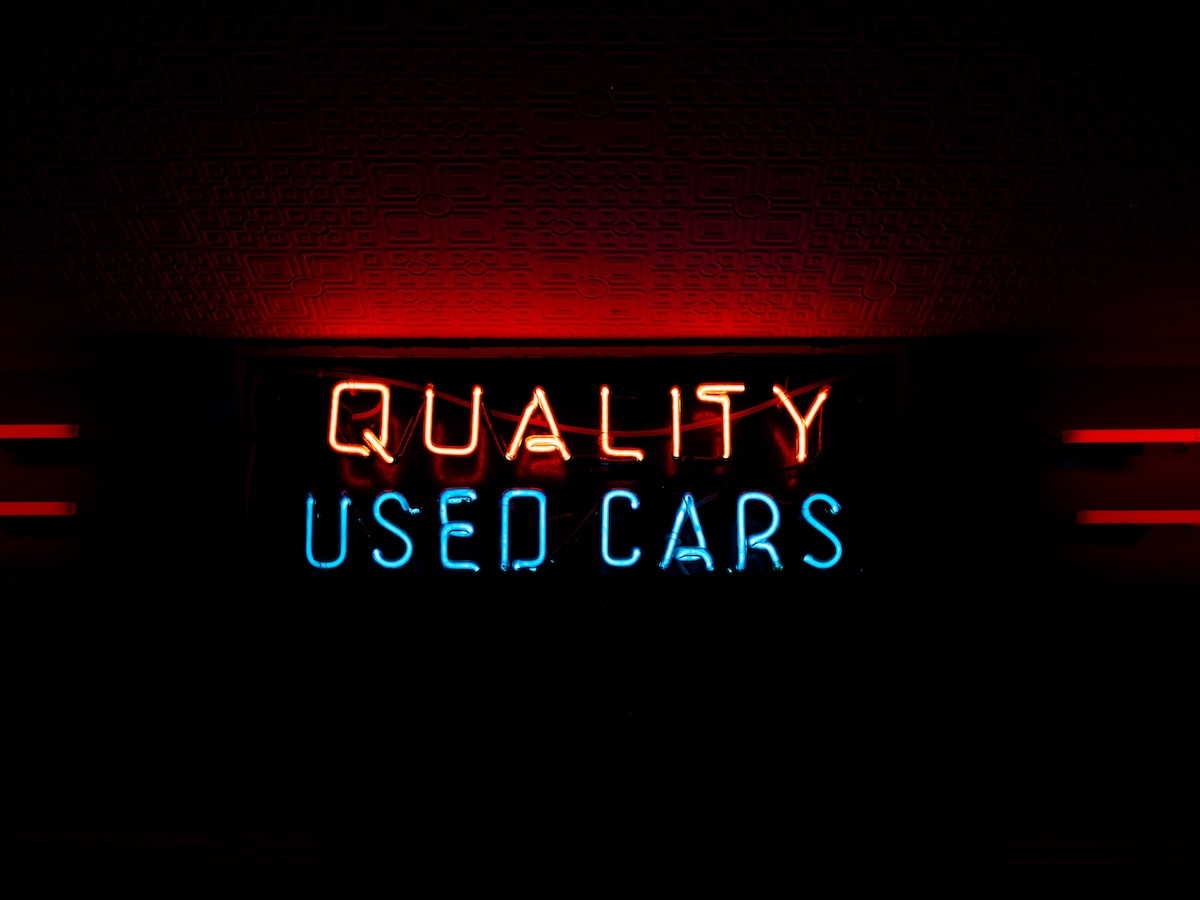 A neon sign displaying the text 'QUALITY USED CARS'