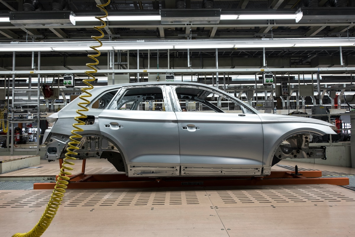 The shell of a car sits on a factory floor midway through being built.