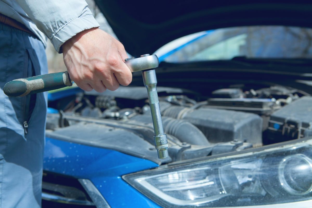 A mechanic holds a ratchet that's working a bolt for a headlight