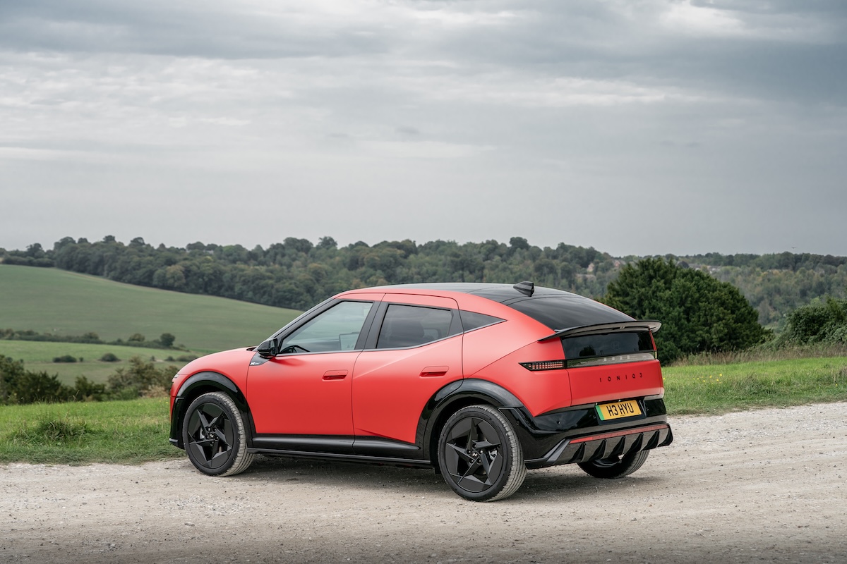 A red Hyundai IONIQ 3 parked on gravel looking out over British countryside