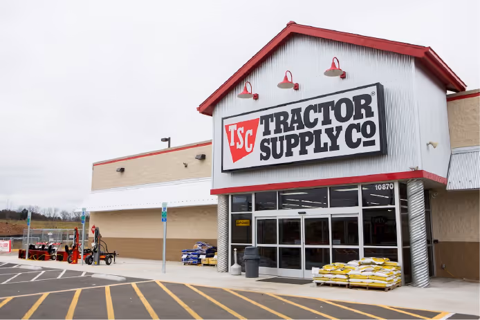 Front entrance of a Tractor Supply Co. store with bags of soil or mulch stacked outside.