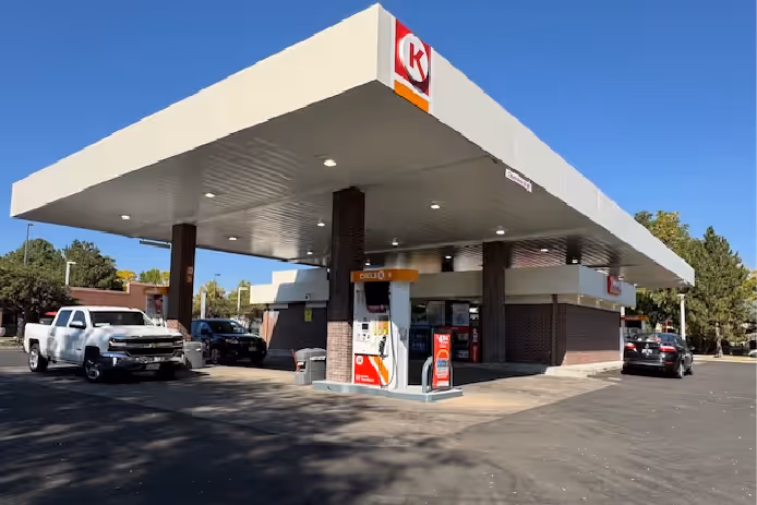 Circle K gas station with pumps under a large white canopy and several cars parked nearby on a sunny day.