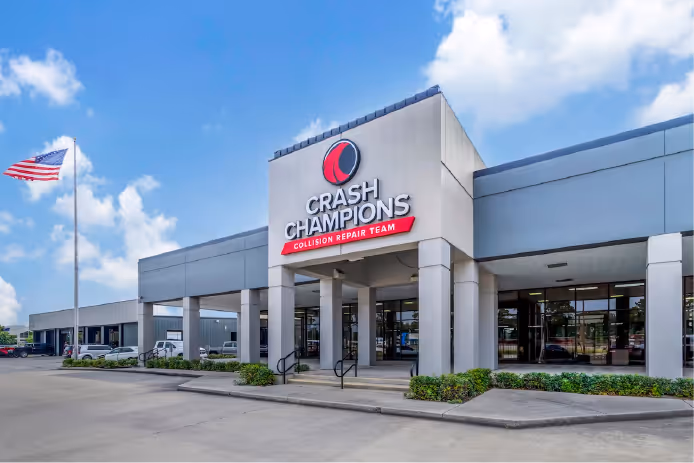 Exterior view of Crash Champions building with its logo and an American flag flying on a pole.