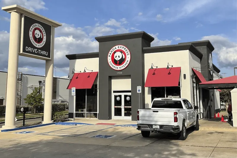 Panda Express restaurant building with a white pickup truck parked in front and a drive-thru sign.