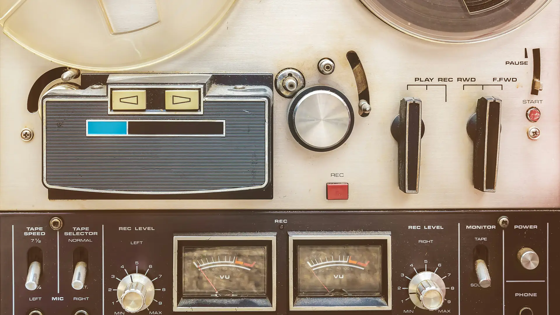 Close-up of a vintage reel-to-reel tape recorder with dials, meters, and tape reels.