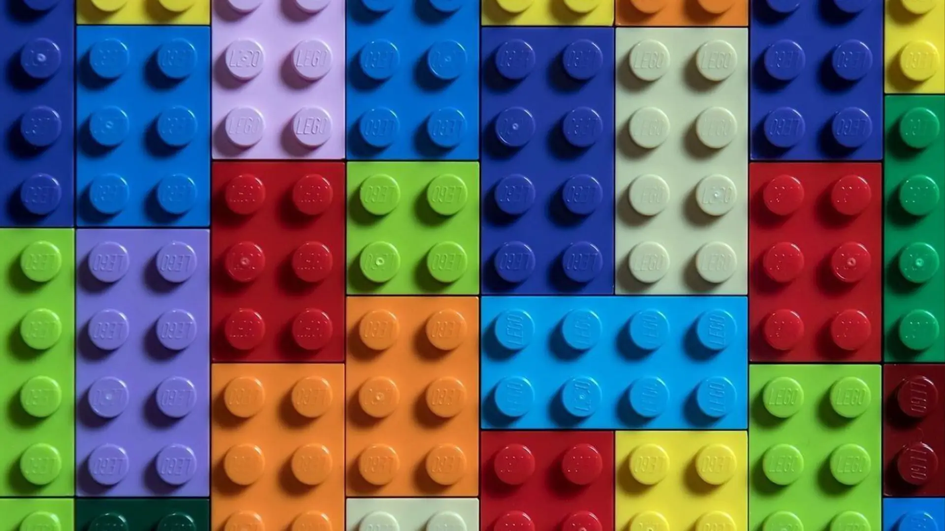 Colorful LEGO bricks arranged closely in a grid pattern with various bright colors.