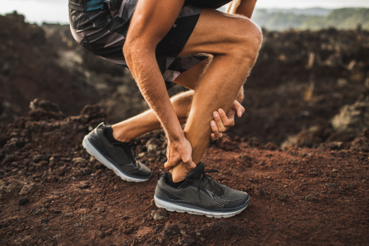 Runner holding ankle after tendonitis strain outdoors