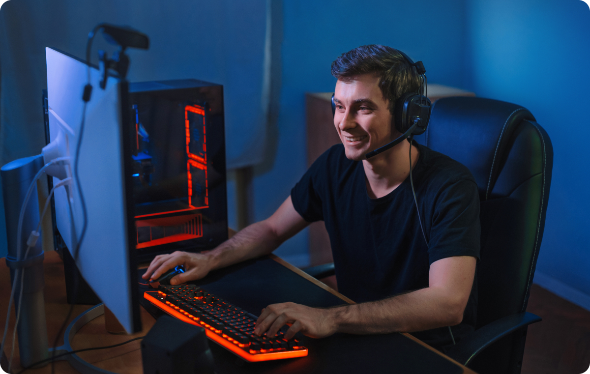 A man smiling with a pair of headphones in front of a computer