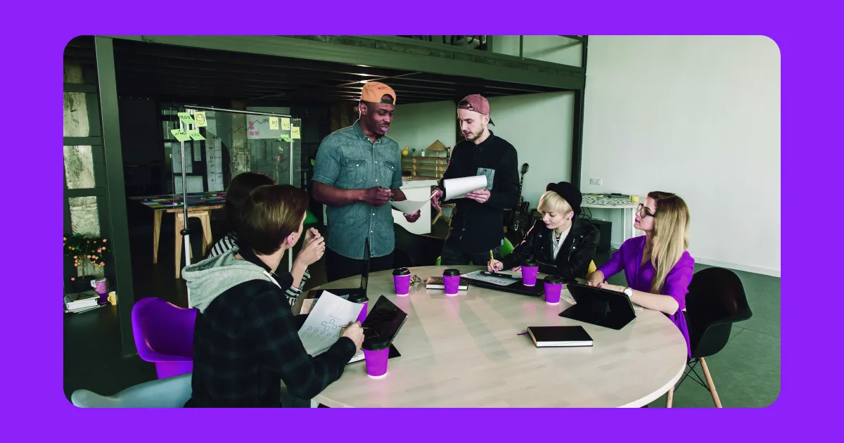 A group of people sitting at a table inside an office.