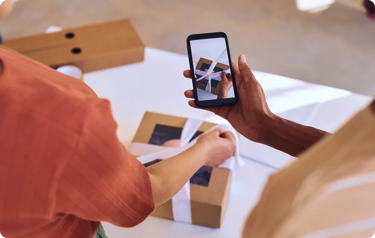 A person opening a box with a phone.