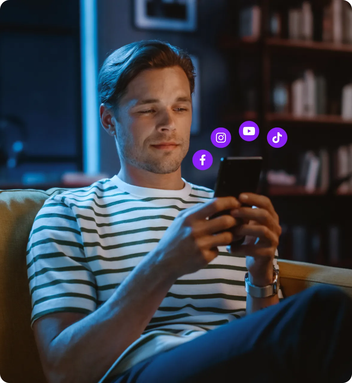 A person using their phone with various social media icons popping from it. 
