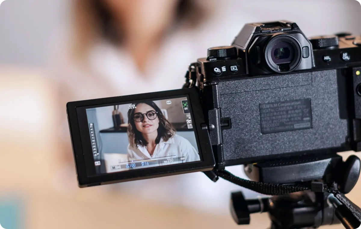 An image of a camera with a flip-out screen filming a woman.