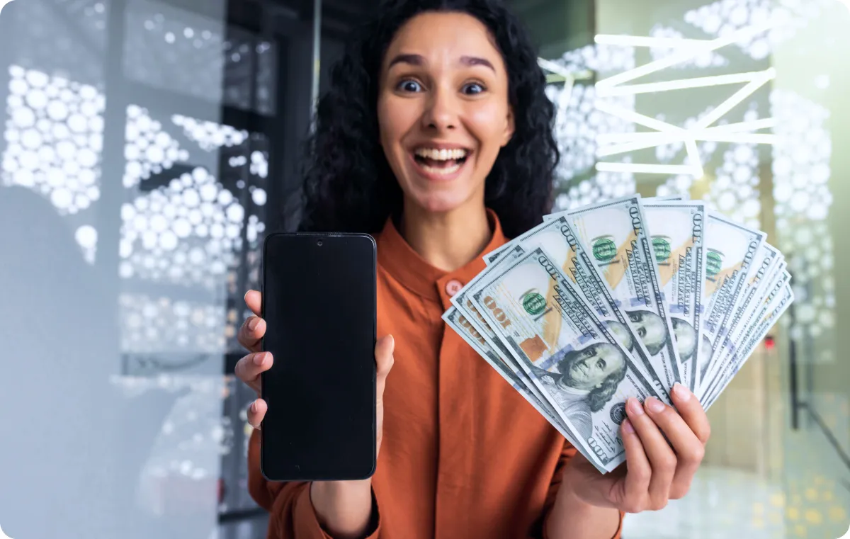 A graphic design of a hand holding a mobile device surrounded by dollar signs.