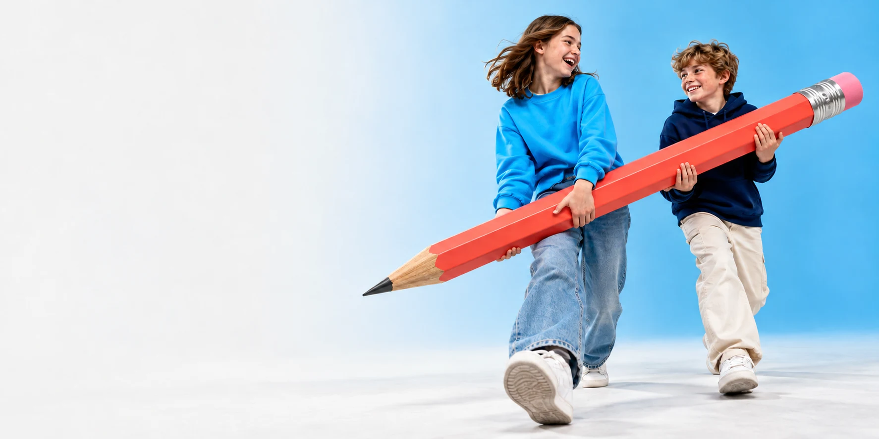 Two students carrying an oversized coral pencil together