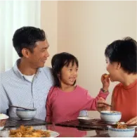 Asian father and young daughter at dinner table