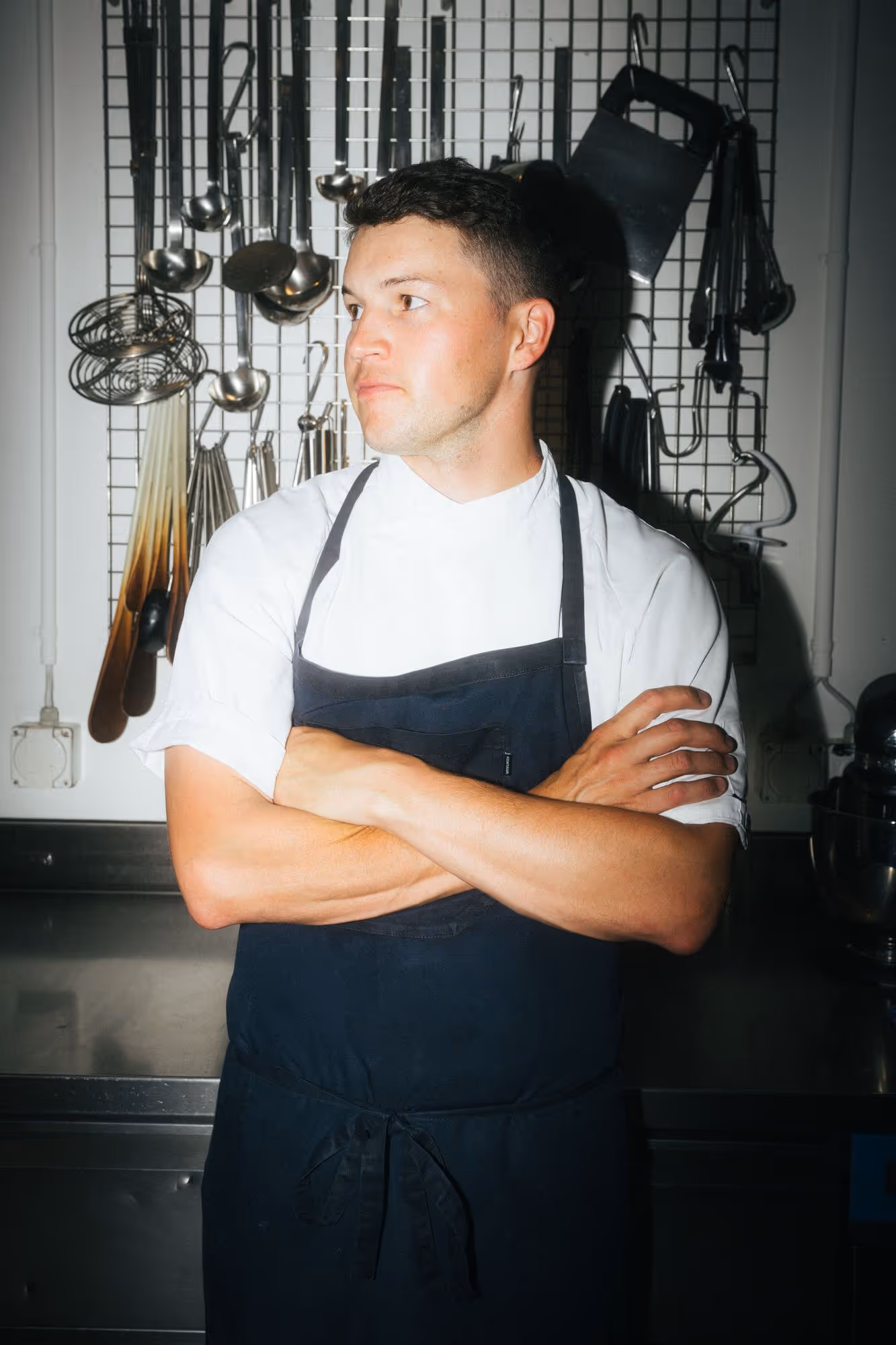 a man in a black apron with his arms crossed