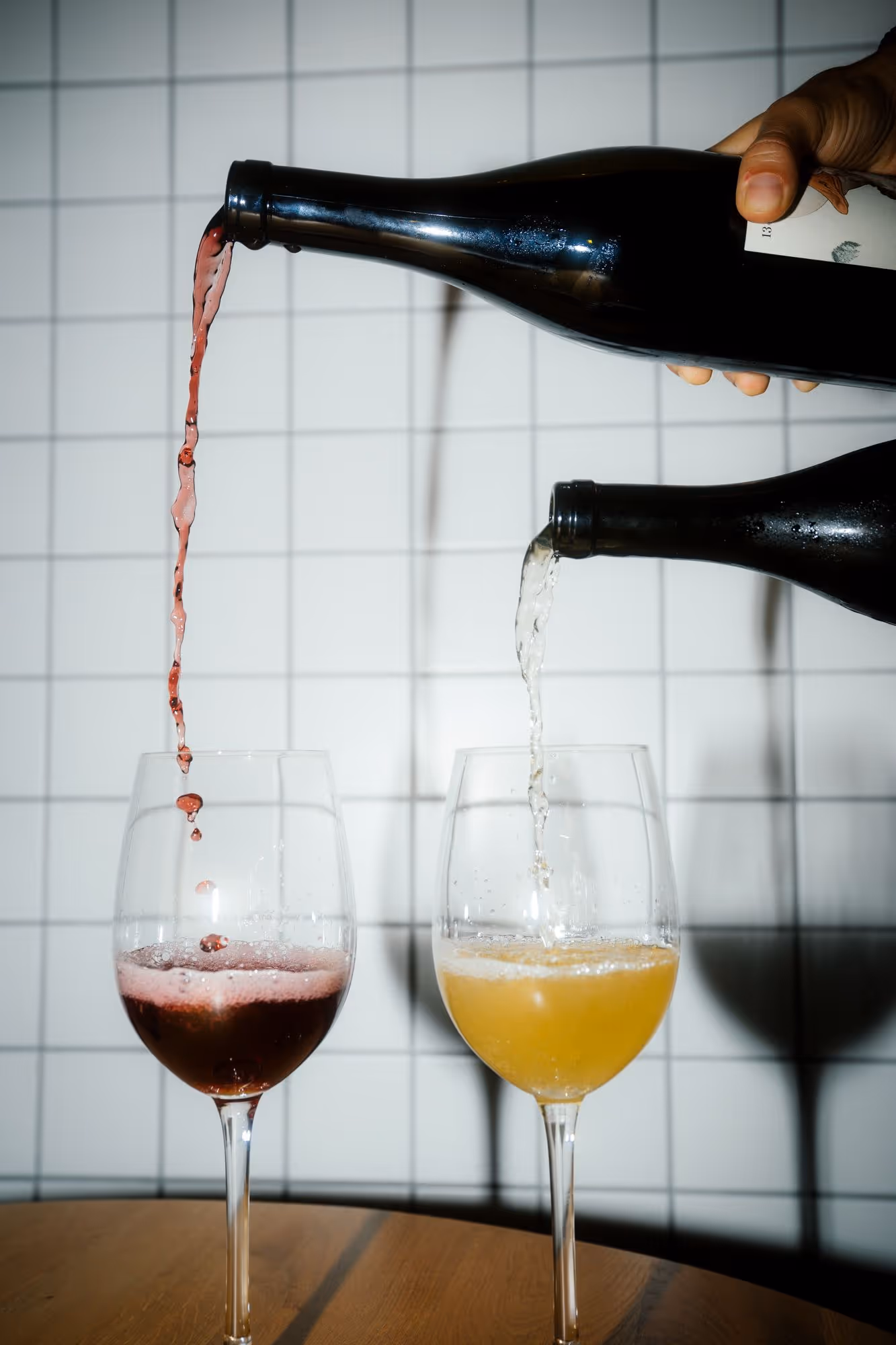 a person pouring wine into glasses