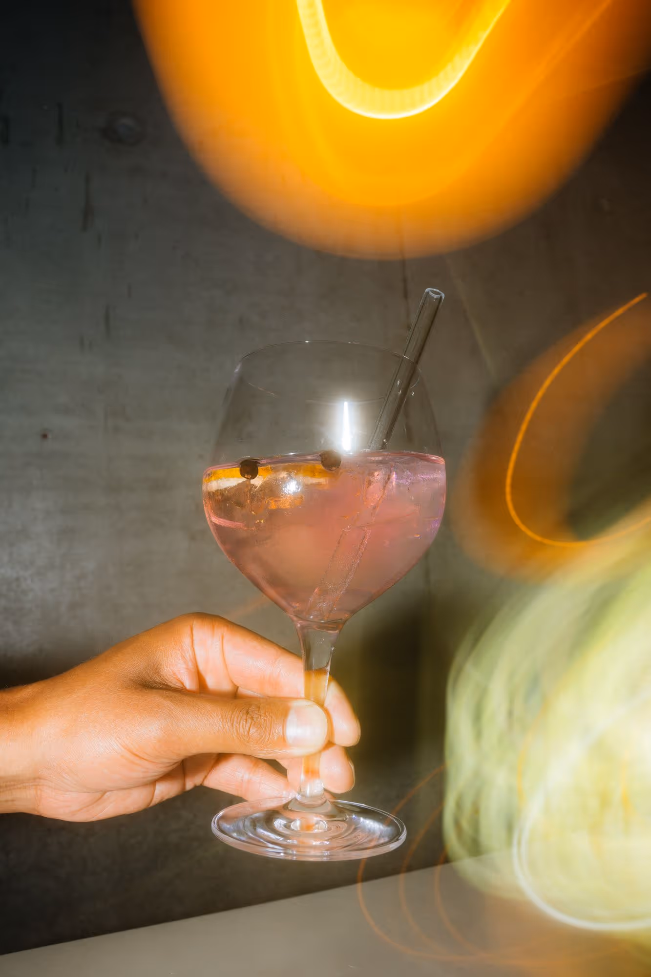 a hand holding a glass of pink liquid