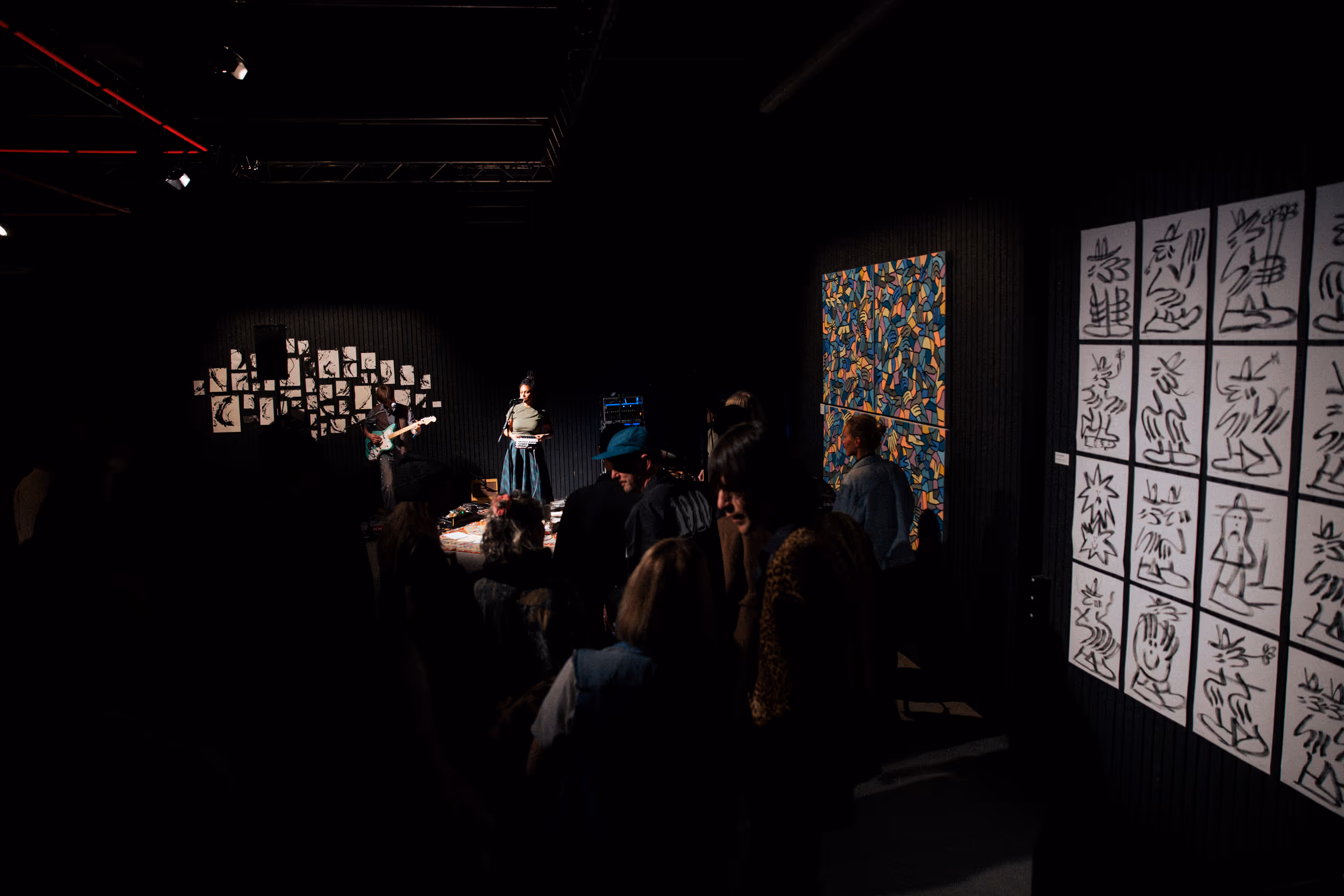 a person playing a guitar in a dark room with a crowd of people