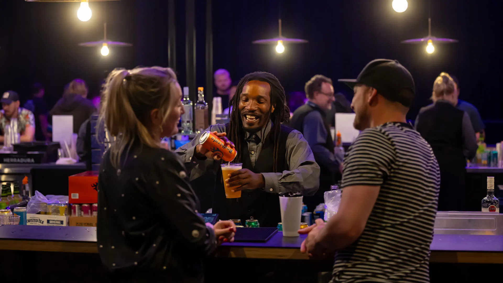 Two guests enjoying the bar at the WAMU Theater and laughing with a bartender.