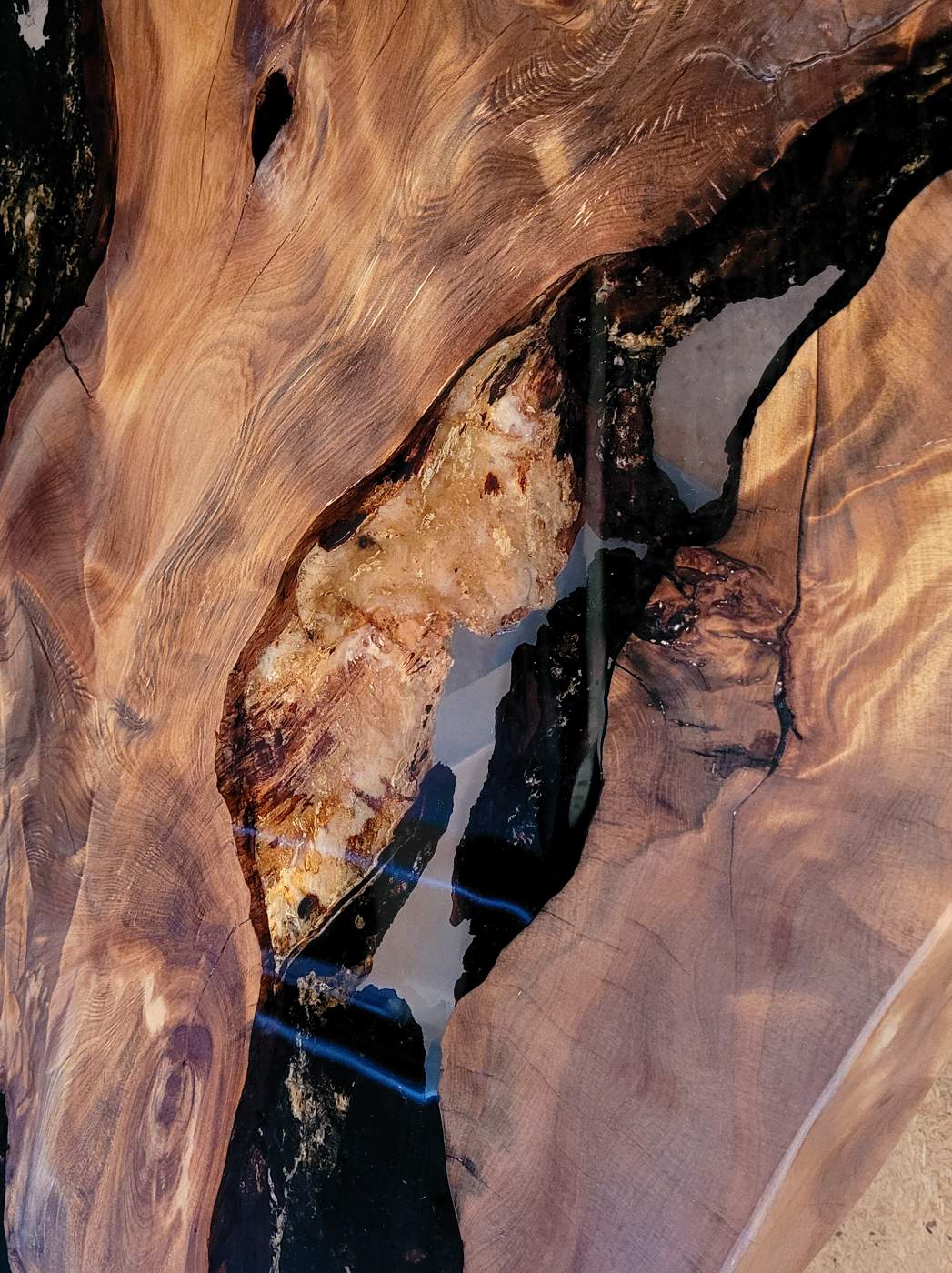 Exclusive table top of a beautiful unique wooden table with golden amber in epoxy resin made from old Kauri wood as an artistic table