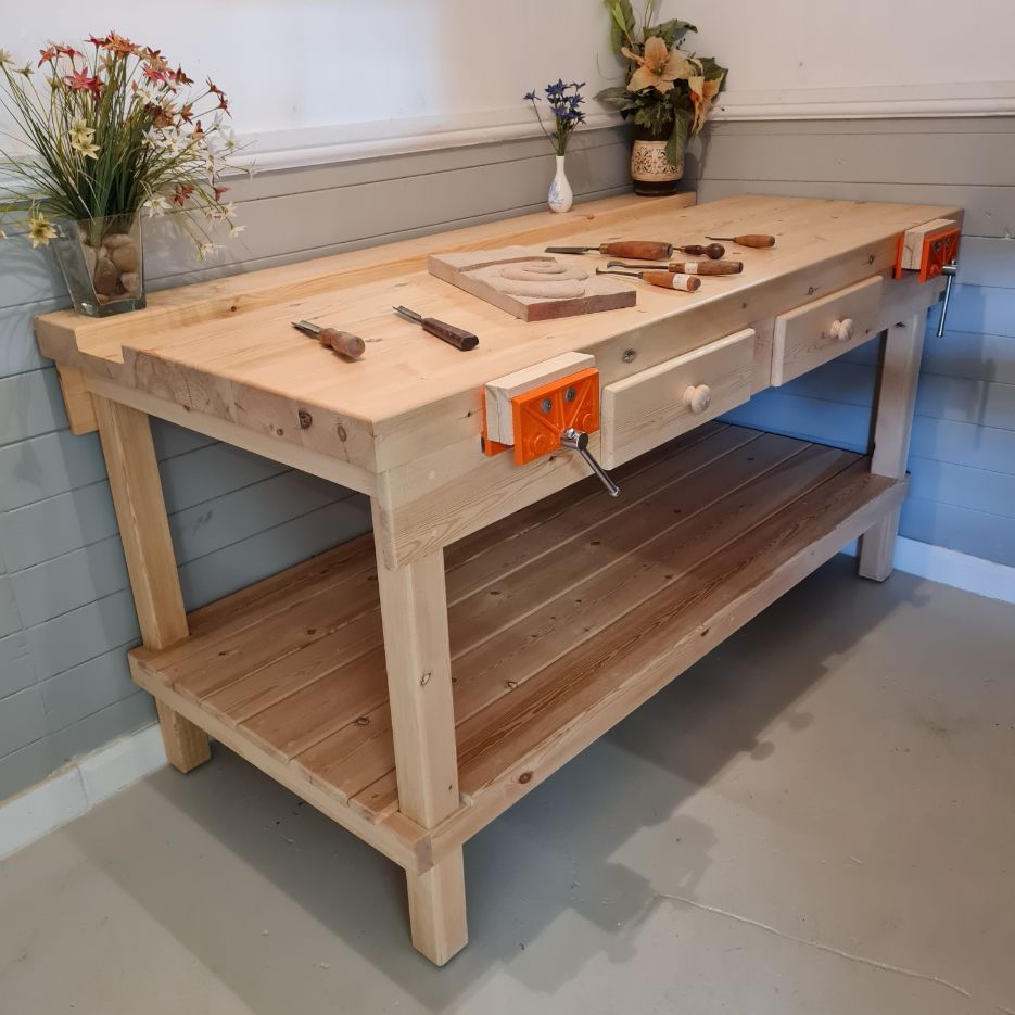 A handmade wooden workbench with drawers and orange vices