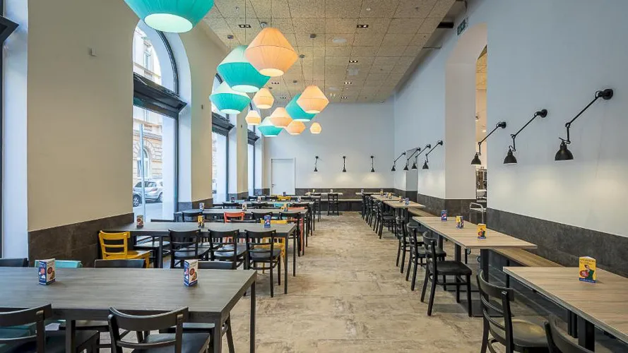A restaurant with tables, chairs, and lamps