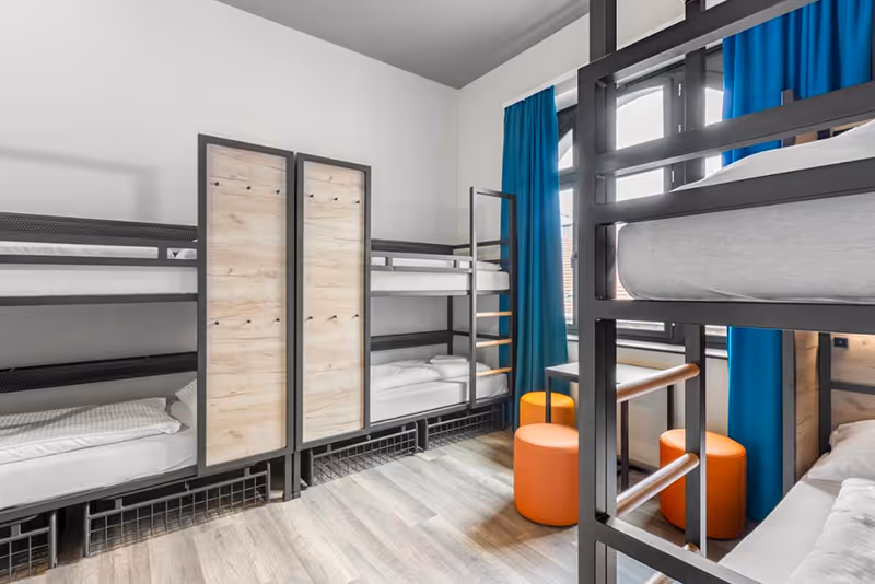 A room filled with bunk beds and orange stools