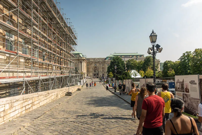 A group of people walking down a street next to scaffolding