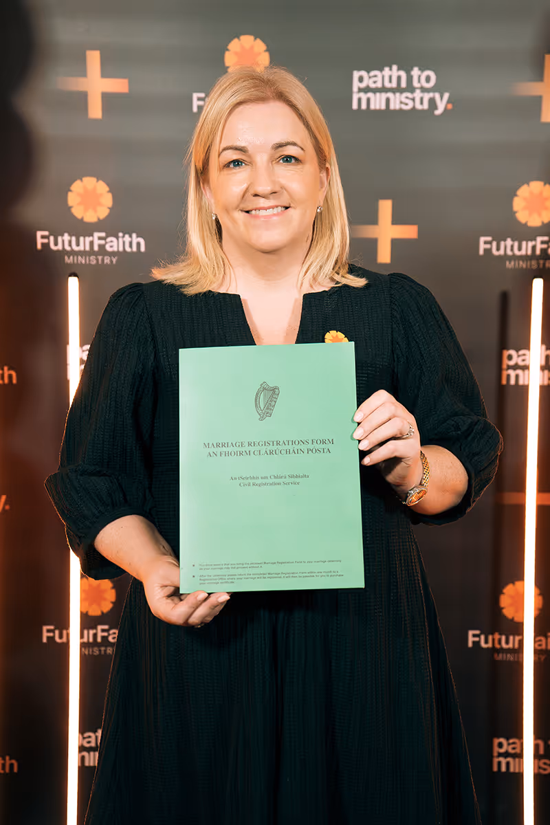 Smiling woman in black dress holding a green Marriage Registrations Form in front of a FuturFaith Ministry backdrop.