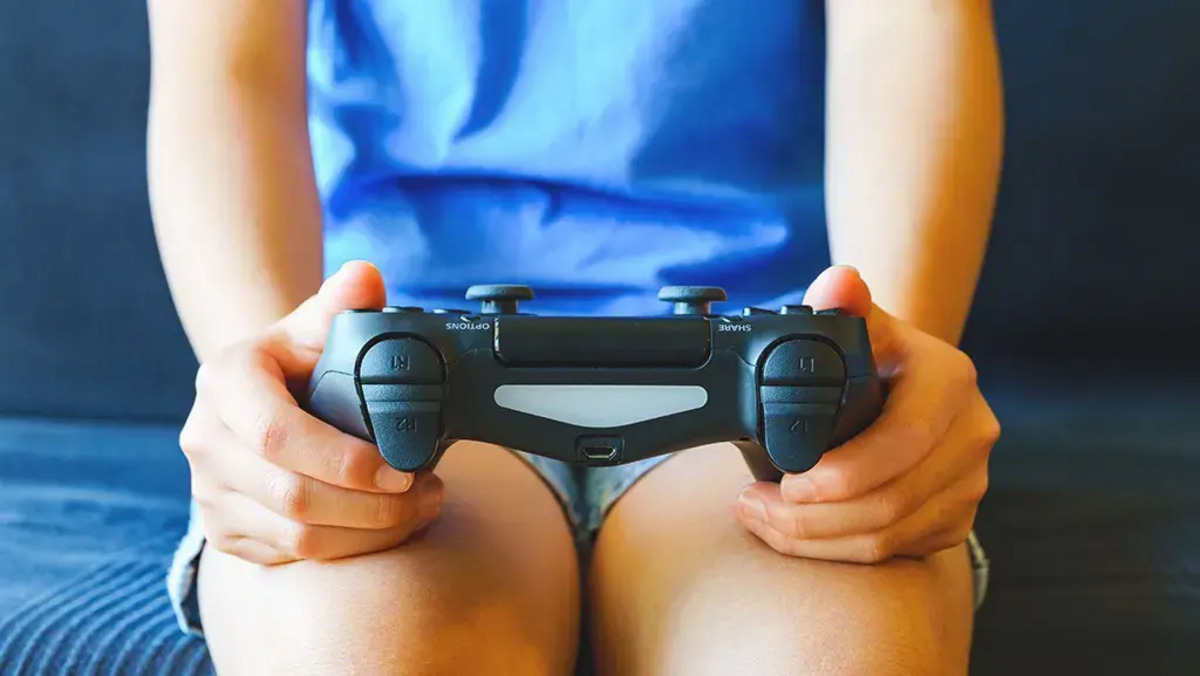 A person holding a PS4 controller.