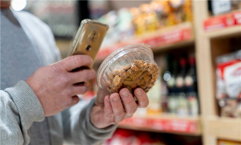Hand reaches into cardboard box with empty cans and plastic bags