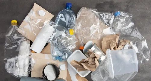 En bunke ren emballage som plastikflasker og papkasser på et trægulv