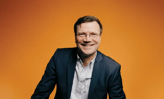 Portrait of Per Ahlmann Andersen in front of an orange background