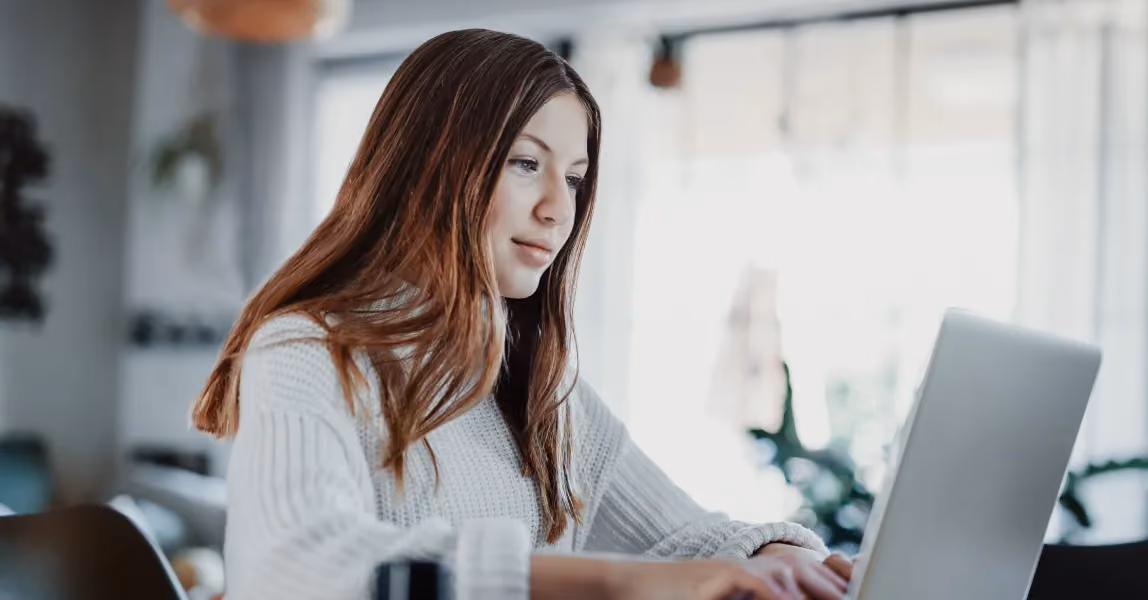 Young woman using laptop in a modern office environment, illustrating user engagement with the Sharry workplace mobile app