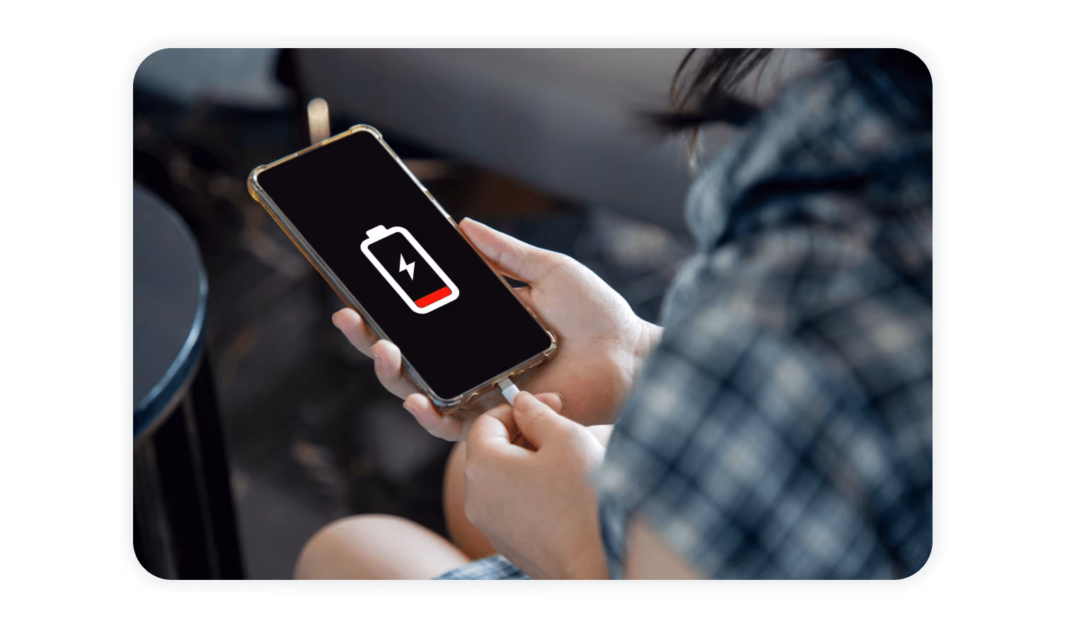 Person holding iPhone with low battery icon on screen, illustrating Apple Wallet badge access even when the phone battery is depleted